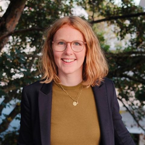 Porträt von Meike Hornbostel, lächelnd vor Baumkronen.